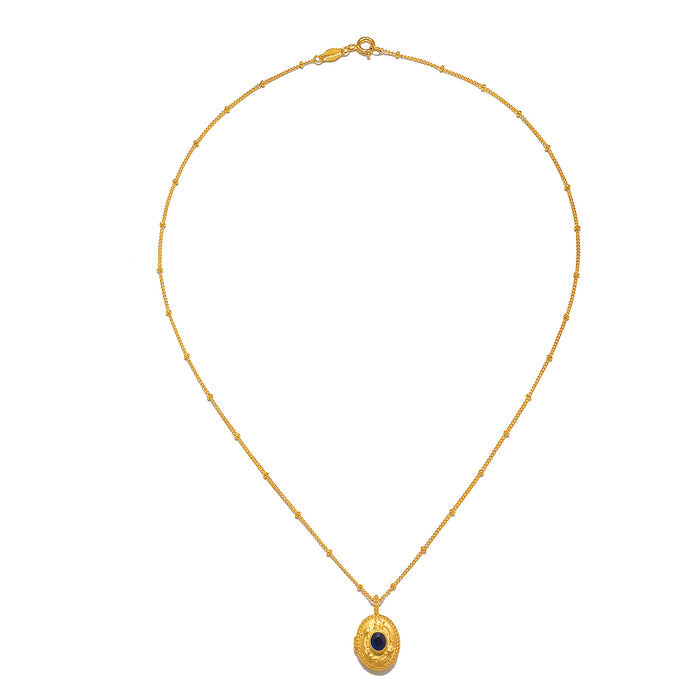 Lotus Sapphire Birthstone Locket Necklace - September laid flat, highlighting the intricate locket and its chain. This talisman, made from 18kt gold plate, embodies spiritual meanings related to yoga, meditation, and the zodiac, making it a perfect charm for personal growth and protection.