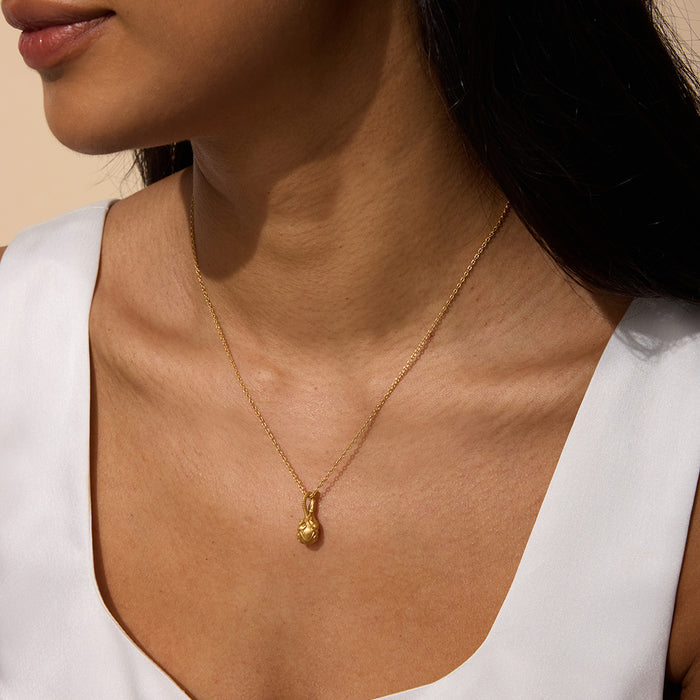 A woman wearing the Love Potion Lotus Vessel Necklace, showcasing its elegant design. This piece of spiritual jewelry symbolizes new beginnings and transformation, making it a perfect talisman for meditation and manifestation. Ideal for yoga enthusiasts and those seeking meaningful accessories for protection, this necklace embodies the essence of the sun and moon.
