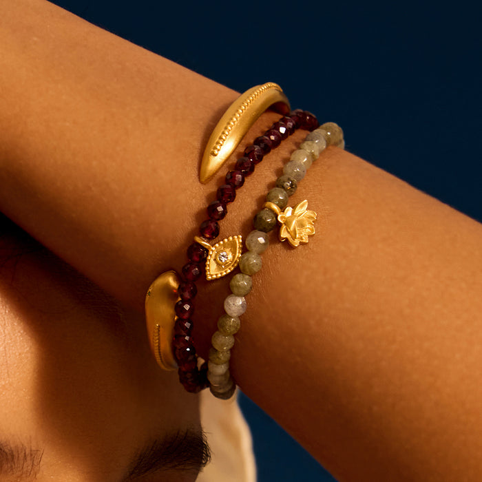 Close-up of the Loving Protection Garnet Evil Eye Bracelet, adorned with garnet and golden accents, ideal for meditation rituals. This spiritual jewelry is not just an adornment but a talisman of protection, enriching the meaning of your yoga and spiritual practices.