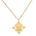 Gold-toned chain necklace with circular coin pendant featuring deity figure and decorative elements.