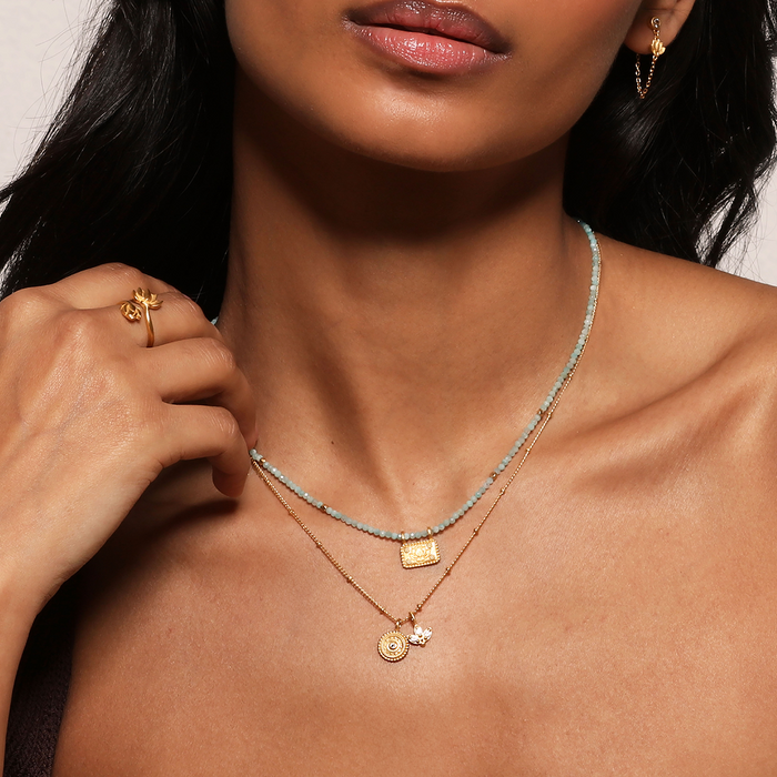 Model showcasing the Manifesting Possibilities Lotus White Topaz Necklace layered with other spiritual jewelry, embracing the essence of manifestation and individuality. A perfect charm for yoga practitioners and those exploring zodiac meanings in their spiritual journey.