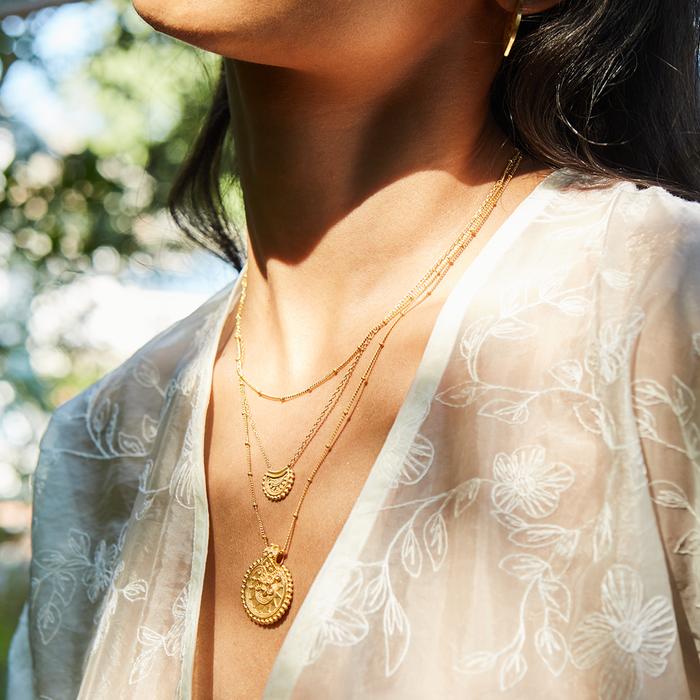Model wearing the Mini Mandala Necklace layered with other golden chains, showcasing its versatile style. This spiritual jewelry makes a thoughtful meditation gift, resonating with the mantra of balance and sacred meaning for those in pursuit of enlightenment.