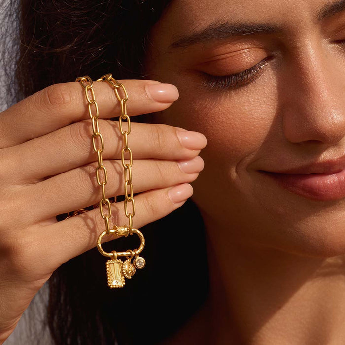 A model gracefully holding the New Beginnings Lotus Charm Holder Necklace, radiating warmth. This jewelry piece represents a journey of self-discovery, embodying the essence of spirituality and protection through its meaningful charm holder design.