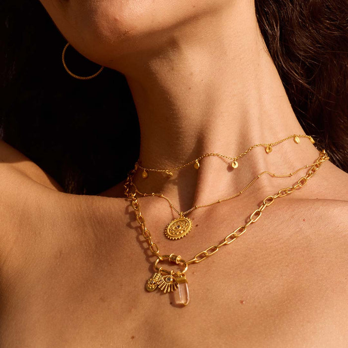 A model displays the New Beginnings Lotus Charm Holder Necklace layered with other necklaces, highlighting its charm-holding feature and the lotus flower engraving. This spiritual jewelry is ideal for meditation, representing meaningful connections and the power of manifestation within one's journey.