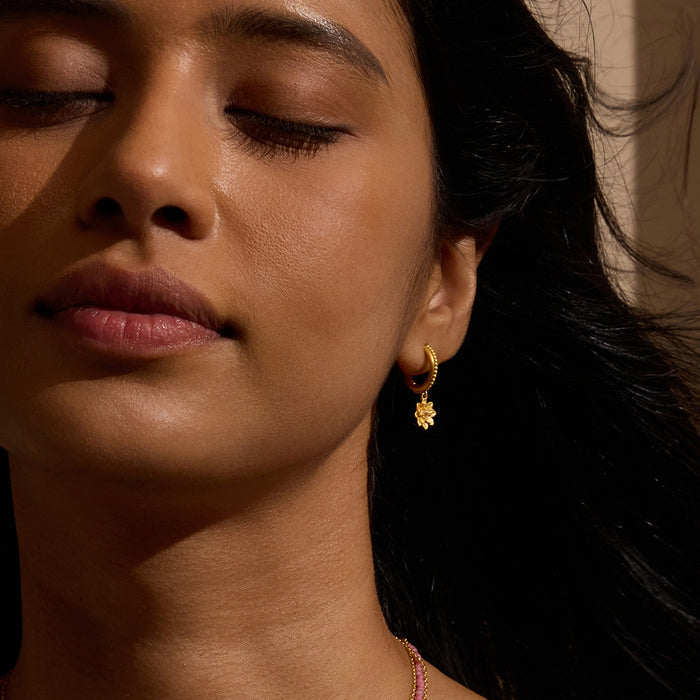 Model showcasing New Chapter Lotus Huggie Earrings, highlighting the elegant design symbolizing renewal and transformation, perfect for yoga enthusiasts and those seeking spiritual meaning and protection.
