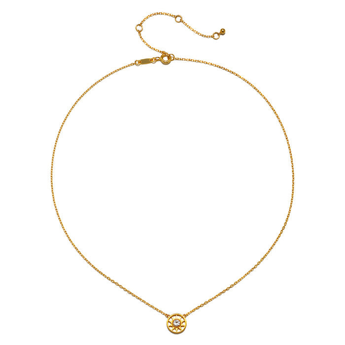 Gold chain necklace with small circular sun pendant set with clear stone at center.