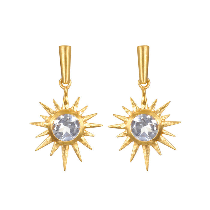 Pair of gold starburst earrings with clear faceted stones in the center and pointed rays radiating outward.