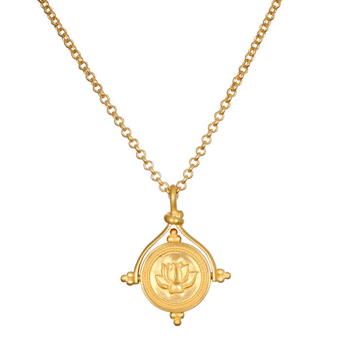 Gold-toned necklace with rotating circular pendant featuring lotus flower design and four compass-point protrusions.