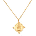 Gold-toned necklace with round pendant featuring embossed Ganesha figure and decorative side details on chain.