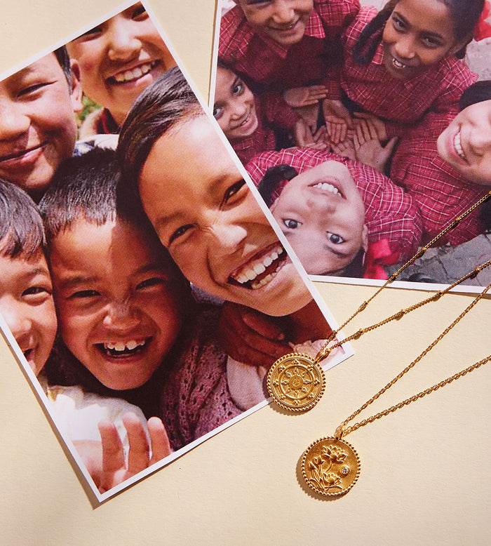 Gold-toned circular pendant necklaces with detailed engravings on fine chains displayed next to family photographs.