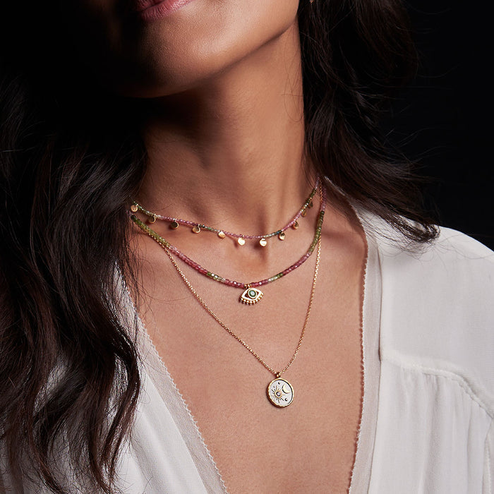 A woman wearing the Peace & Protection Tourmaline Choker alongside other layered necklaces, showcasing the spiritual jewelry's unique design. This serene piece is perfect for meditation gifts, embodying the essence of mantra and yoga while representing meaningful protection and sacred symbolism.