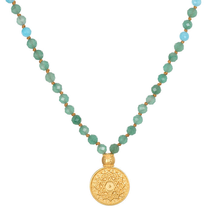 Mala necklace with green faceted beads, light blue accent beads, gold spacers, and gold circular pendant with geometric star