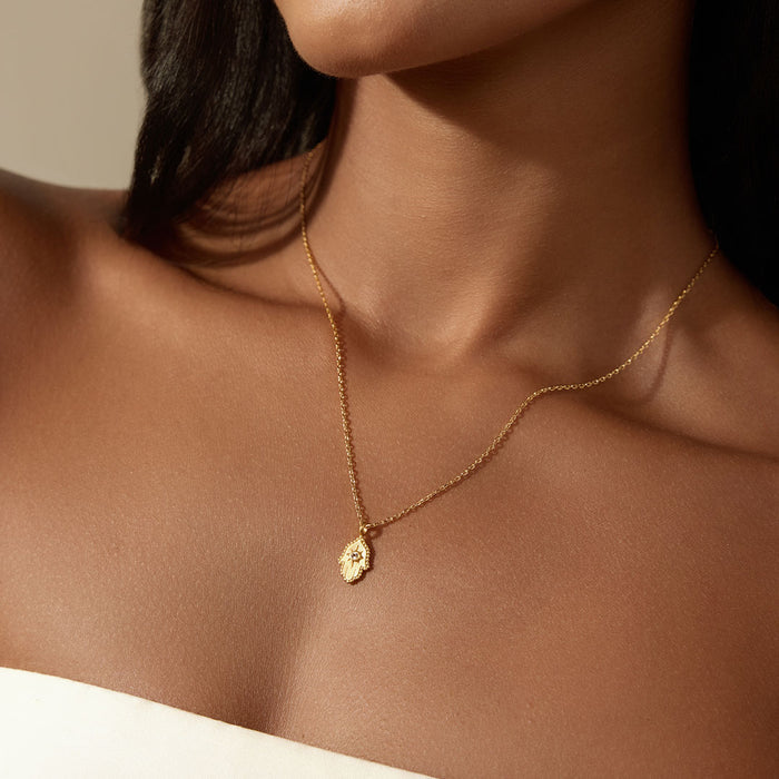 Close-up of a woman wearing the Protective Hand White Topaz Hamsa Necklace, showcasing the delicate design of the hamsa hand pendant. This spiritual jewelry piece serves as a protective talisman, aligning with themes of manifestation, meditation, and meaningful energy in one's spiritual journey.