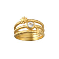 Three-piece gold ring set with sun motif, circular crystal stone, and textured bands stacked together.