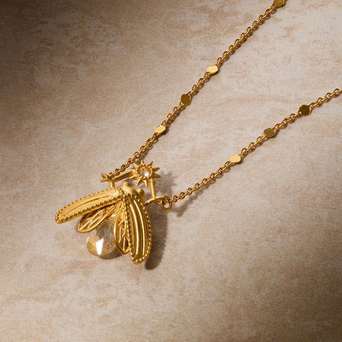 Gold-toned firefly pendant necklace with clear faceted stone and detailed wings on delicate chain.