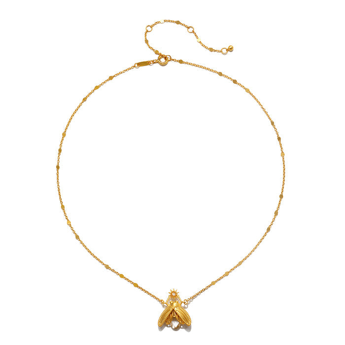 Gold-tone chain necklace with delicate beaded links and a faceted crystal pendant shaped like a firefly at the center.