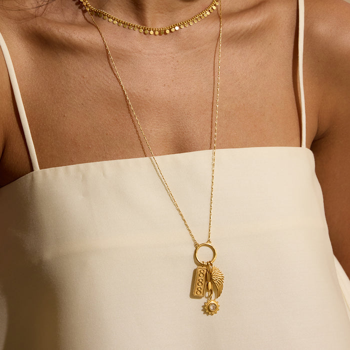 Gold-toned pendant necklace with wing charm, rectangular detail, and small circular accent on delicate chain.