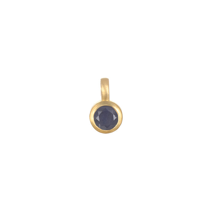 Close-up of the Sapphire Bezel Charm featuring a deep blue sapphire set in 18kt gold plate, representing trust, protection, and love. A beautiful piece of spiritual jewelry for those who seek meaning and manifestation in life, ideal for adding to charm necklaces. Perfect for yoga practitioners and meditation enthusiasts.