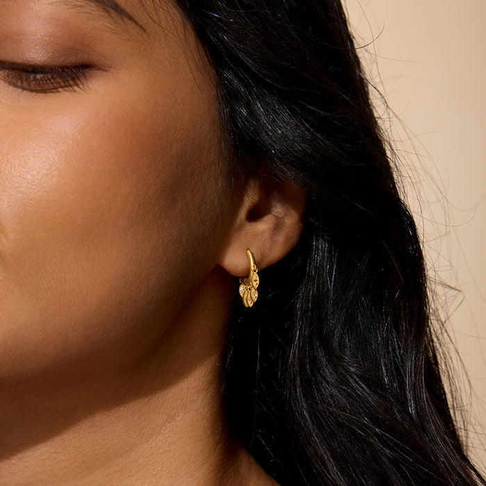 A woman wearing Scatter Light Huggie Earrings, showcasing the elegant design which symbolizes spiritual jewelry for meditation and manifestation. The earrings feature white topaz, connecting with meanings of protection and blessings related to the sun and moon, making them perfect for yoga and personal growth.
