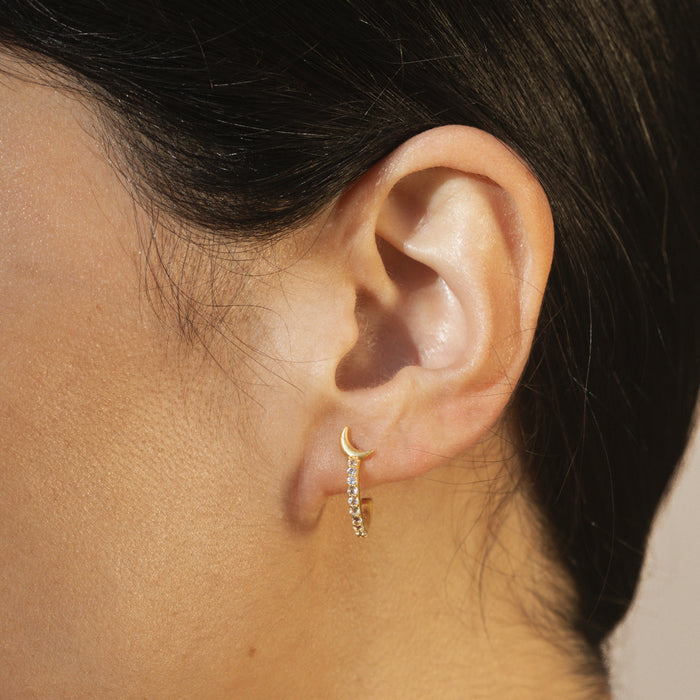 Profile view of the Scattered Stardust Celestial Moon and Star Pavé Hoop Earrings showcasing their elegant design on a woman’s ear. These earrings represent meaningful energies from the sun and moon, serving as a talisman for those exploring spirituality, protection, and manifestation.