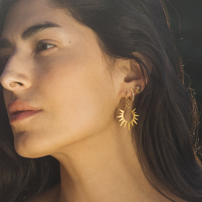 Close-up of a model wearing Scattered Stardust Celestial Moon and Star Pavé Hoop Earrings, 18kt gold plated with white topaz accents, symbolizing spiritual jewelry, meditation, and meaningful talismans for protection, ideal for yoga and manifestation.