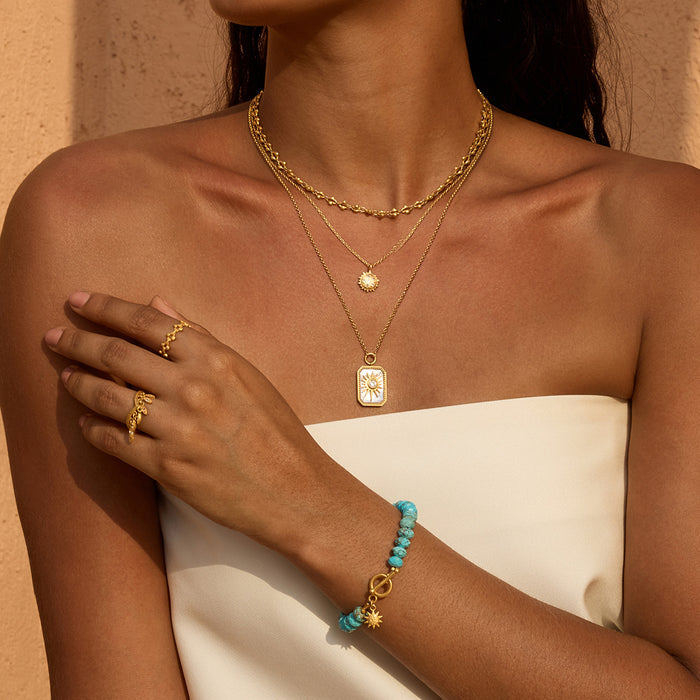 Turquoise beaded bracelet with gold-tone toggle clasp and star charm on model's wrist.