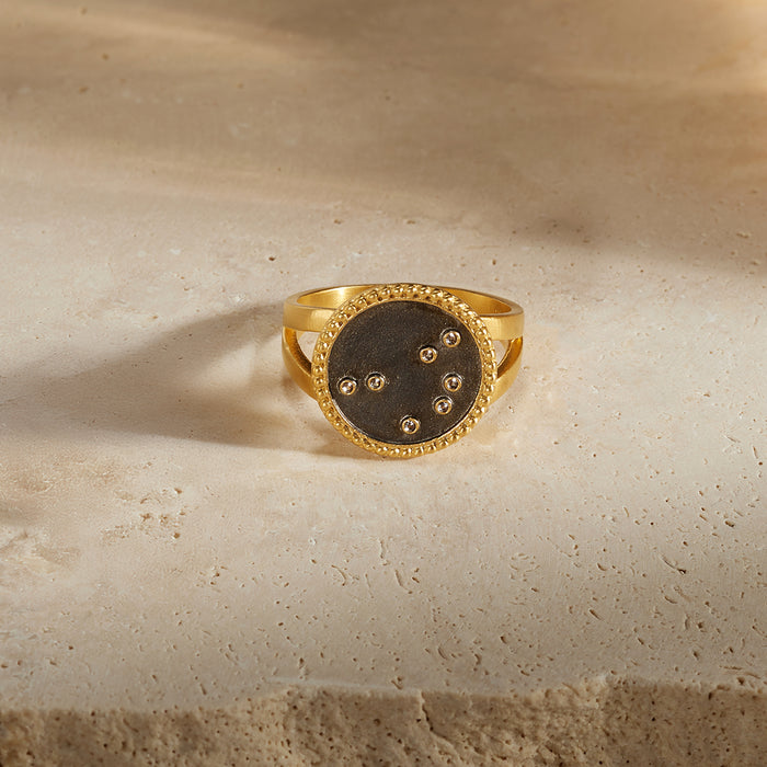 The Shine in Sisterhood Constellation Ring features an 18kt gold plated design with a gunmetal background and seven sparkling pyrite stars, symbolizing connection and sisterhood in spiritual jewelry. This unique piece serves as a talisman for meditation and meaningful manifestation, embodying the essence of zodiac inspirations like the Pleiades. Perfect for yogis seeking spiritual protection and beauty under the sun and moon.