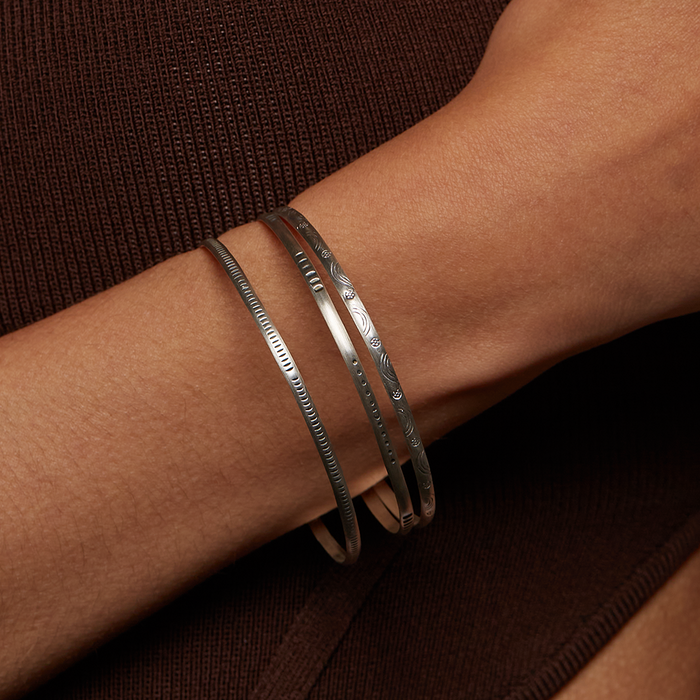 Close-up of a Silver Etched Bracelet Bangle titled Melody worn on a wrist, highlighting its elegant design, ideal for meaningful adornment in spiritual practices like yoga and meditation, serving as a protective amulet.