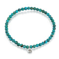 Silver Turquoise Om Stretch Bracelet - Inner Peace, featuring small turquoise stones encircling a sacred Om charm, perfect for adding a meaningful touch to your spiritual jewelry collection. This bracelet represents health and self-expression, making it a wonderful gift for meditation, yoga, and manifestation enthusiasts.