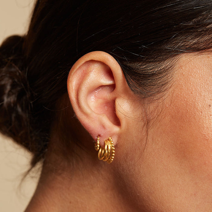 Close-up image of a model wearing Simple Treasure Dot Hoop Gold Earrings, showcasing their elegant design that symbolizes protection and spirituality. A perfect talisman for those who embrace meditation and meaningful living.