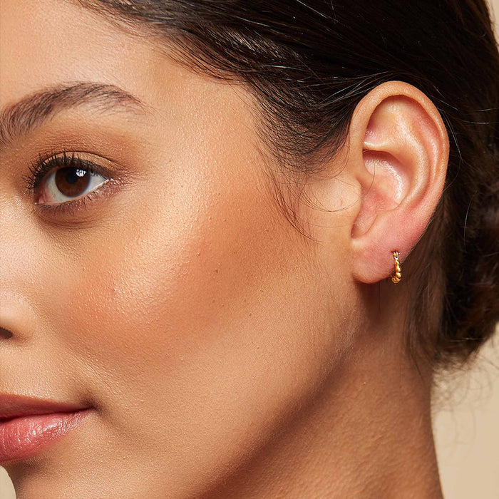 Profile view of a model wearing Simple Treasure Dot Hoop Gold Earrings, exemplifying how these spiritual jewelry pieces complement personal style. Ideal for manifestation, they resonate with sun and moon energies.