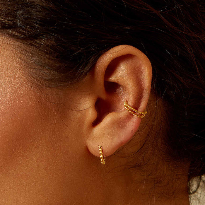 Artistic shot of Simple Treasure Dot Hoop Gold Earrings worn in a layered style on a model, highlighting their versatility in spiritual jewelry. Perfect for yoga enthusiasts seeking meaningful accessories that embody protection and charm.