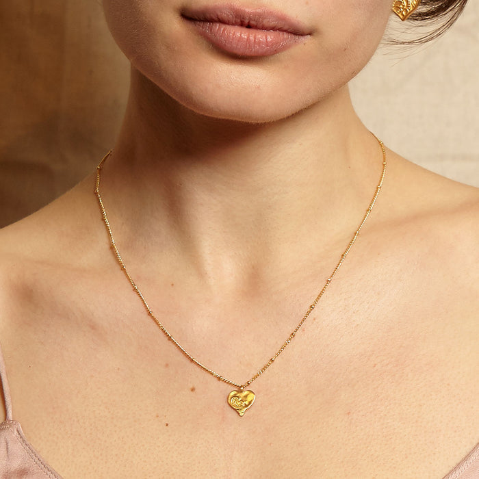 Close-up of a model wearing the Spirit of Love Gold Heart Necklace, showcasing its intricate design, ideal for yoga practices or as a unique piece of spiritual jewelry representing love and compassion.