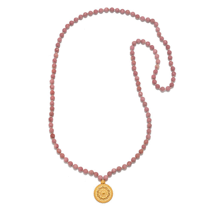 Flat lay of the Spiritual Evolution Rhodonite Mala displaying its 108 rhodonite beads and gold pendant, a beautiful talisman for protection and meditation.