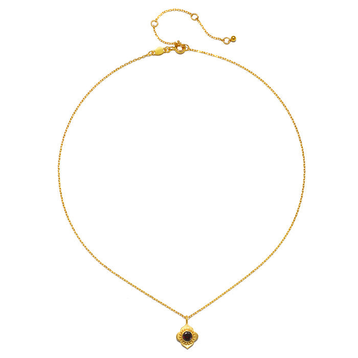Spiritual Strength Garnet Lotus Necklace displayed on a flat surface, highlighting its delicate gold chain and beautiful pendant, ideal for anyone interested in spiritual, meaningful jewelry for yoga and talismanic properties.