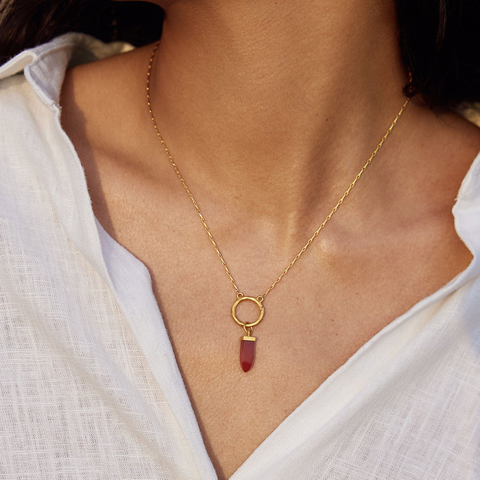 Stay Grounded Red Onyx Dagger Charm worn on a delicate gold necklace, showcasing its beauty and significance. This meaningful spiritual jewelry piece is perfect for grounding energy, linked to zodiac traits and ideal for meditation, bringing protection and balance to your spiritual journey.
