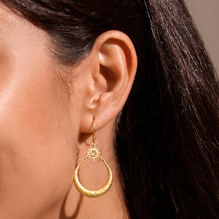 Close-up of a model wearing Stellar Sisterhood Moonstone Hoops, showcasing their elegant design in hammered 18kt gold plate with moonstone. This spiritual jewelry serves as a talisman for inspiration and connection, ideal for meditation, yoga, and reflecting on the meaning of life.