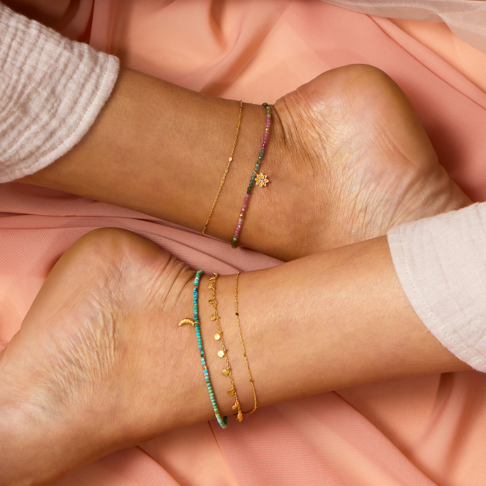 A stylish combination of anklets including the Step Into Light Shimmering Chain Anklet, accented with colorful beads, symbolizing the connection to the sun and moon, ideal for spiritual practices such as yoga and meditation.
