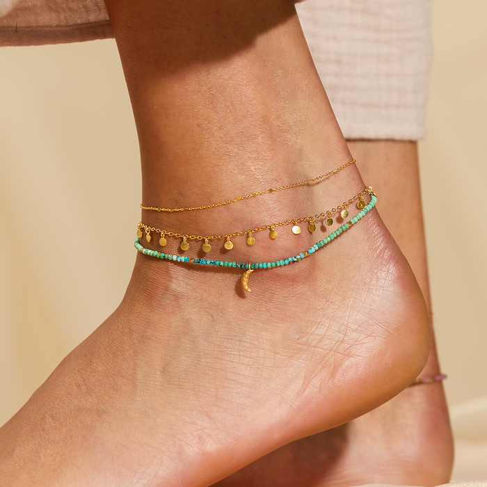 The Step Into Light Shimmering Chain Anklet adorned with multiple charms, designed for those who believe in the meaning of spiritual jewelry and its power as a talisman for protection and manifestation during yoga.