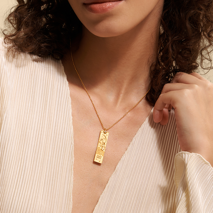 A model elegantly showcases the Story of Aquarius Zodiac Necklace, highlighting the intricate design of the pendant. This spiritual jewelry serves as a protective charm, linking to the zodiac sign Aquarius while inspiring creative energy and a deeper connection to the sun and moon. Ideal for meditation and yoga practices.