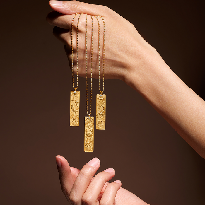 A close-up view of three Aquarius Zodiac Necklaces held gracefully in a hand. These golden pendants serve as meaningful spiritual jewelry, honoring the traits of the Aquarius sign while acting as protective talismans for meditation and mindfulness. Embrace their powerful energy for sun and moon alignment.