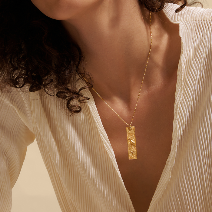 A model wearing the Story of Aries Zodiac Necklace, showcasing the elegant 18kt gold plated pendant that symbolizes Aries. This spiritual talisman is ideal for those who practice yoga and seek a meaningful connection with the sun and moon.