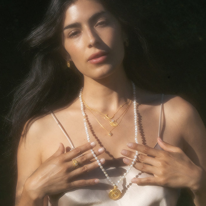 A model wearing the Tranquil Dawn White Opal Sun Mala, showcasing the beautiful white opal beads that symbolize inner peace and health, along with a vibrant sun pendant, perfect for spiritual jewelry, meditation, and manifestation.