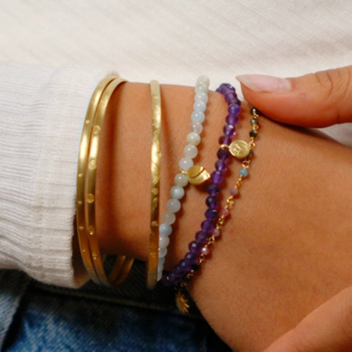 A stylish display of the Tranquility Lotus Amethyst Gemstone Bracelet among other bracelets on a wrist, representing spiritual jewelry that embodies peace and new beginnings, perfect as meditation gifts or symbolic items for manifestation, sacred protection, and yoga practice.