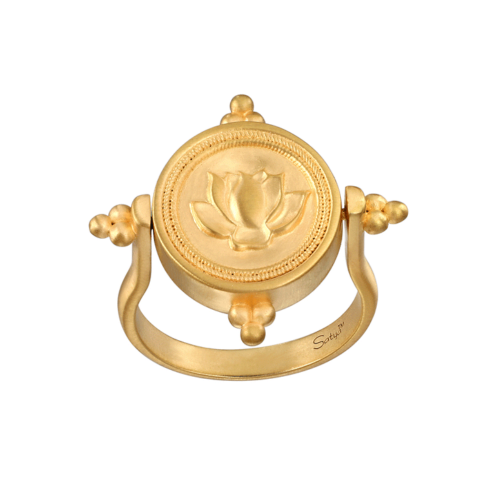 Gold-toned spinner ring with lotus flower medallion center and rotating beaded accents on curved band.