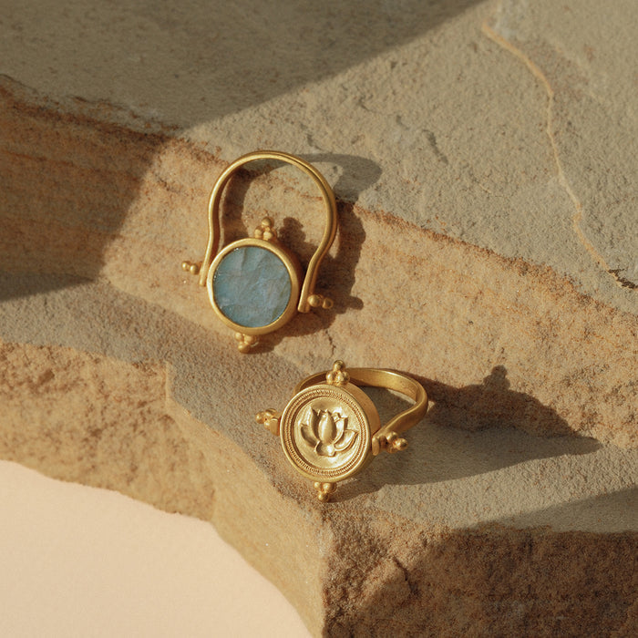 Gold spinner ring with blue labradorite stone on top band and lotus engraving on rotating bottom band.