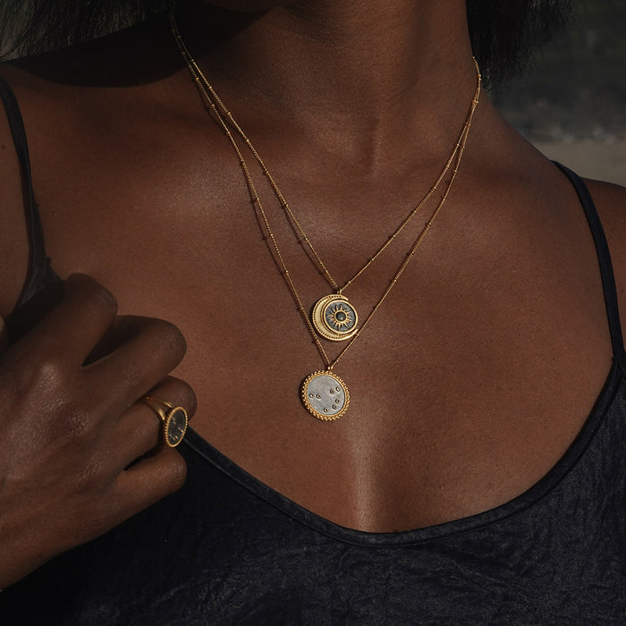 Stylish layering of the United in Light Spinning Pendant Necklace with other necklaces, emphasizing its celestial theme with the crescent moon and sun. This spiritual jewelry piece represents protection and unity, ideal for those seeking meaning and guidance in their meditation and yoga practices.
