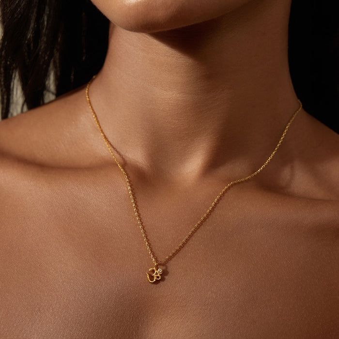 Model wearing the Universal Connection White Topaz Om Necklace, showcasing the beautiful Om symbol in 18kt gold plate. This spiritual jewelry enhances meditation practices, offering a meaningful connection to manifestation and spiritual protection during yoga.