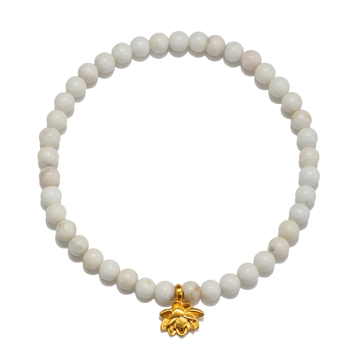 Walk in Harmony Lotus White Turquoise Gemstone Bracelet featuring smooth round white turquoise beads and a delicate golden lotus flower charm. This spiritual jewelry embodies the essence of meditation and protection, making it a meaningful talisman for yoga enthusiasts and those seeking harmony in their lives. Perfect for manifestation and as a zodiac charm, it serves as a reminder of new beginnings and infinite potential.